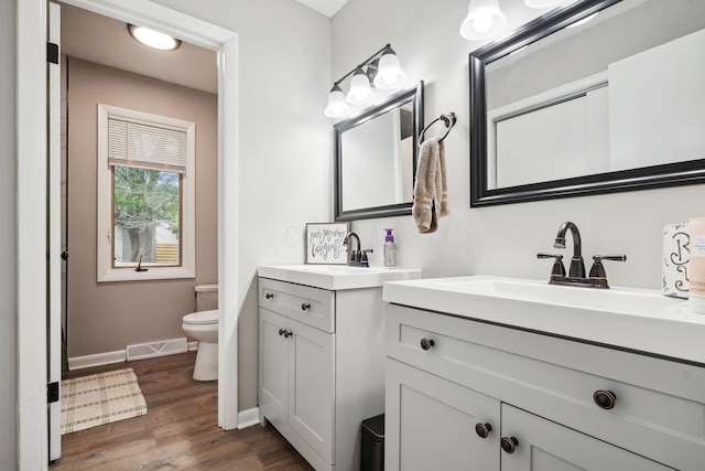710 Cloverleaf Ct, Mansfield, OH 44904 - full bathroom with toilet, baseboards, two vanities, and wood finished floors