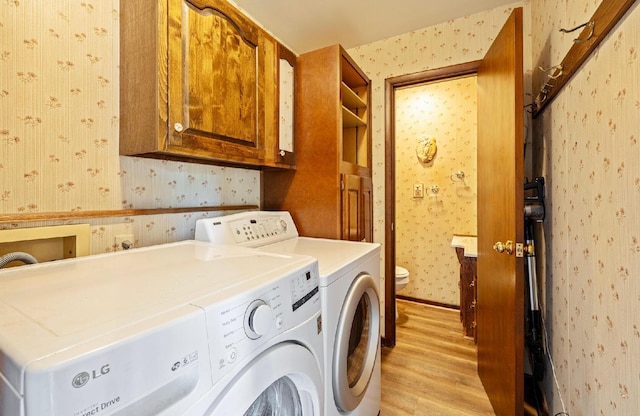 300 Stockbridge Rd, Columbus, OH 43207 - laundry room featuring wallpapered walls, independent washer and dryer, light wood finished floors, and cabinet space