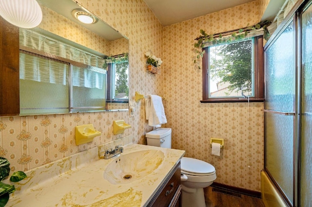 300 Stockbridge Rd, Columbus, OH 43207 - full bathroom with toilet, vanity, wood finished floors, shower / bath combination with glass door, and wallpapered walls