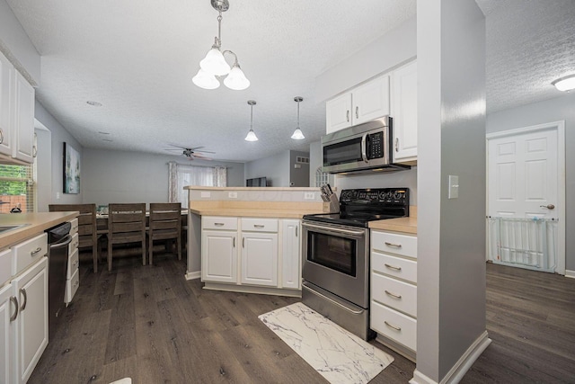 1427 Trabue Woods Blvd, Columbus, OH 43228 - kitchen with appliances with stainless steel finishes, a textured ceiling, dark wood finished floors, a peninsula, and white cabinetry