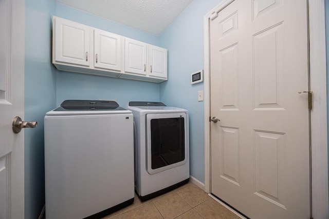 1427 Trabue Woods Blvd, Columbus, OH 43228 - washroom featuring cabinet space, washing machine and clothes dryer, light tile patterned floors, a textured ceiling, and baseboards