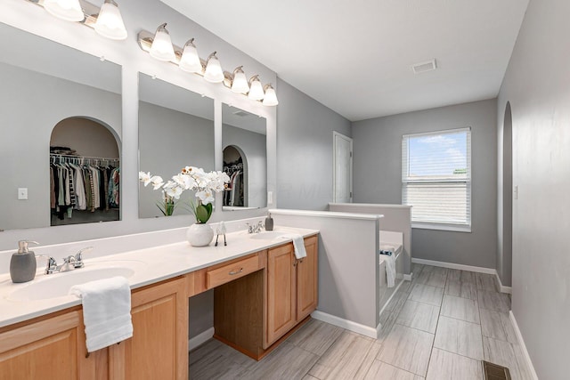 118 Firestone Dr, Delaware, OH 43015 - full bathroom with double vanity, a walk in closet, a garden tub, and baseboards