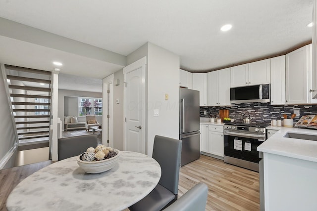 894 Noddymill Ln E Unit 28E, Columbus, OH 43085 - kitchen with appliances with stainless steel finishes, light wood finished floors, light countertops, backsplash, and white cabinetry