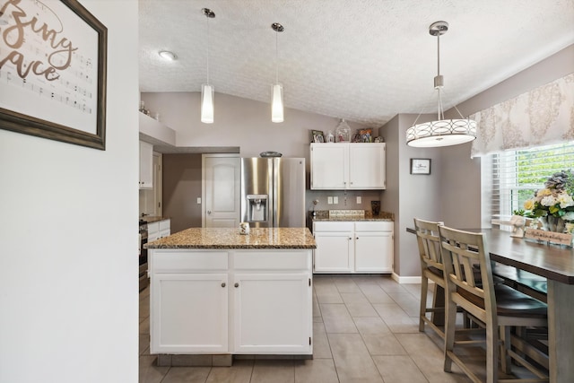 5718 Brook Hollow Dr, Hilliard, OH 43026 - kitchen with stainless steel fridge, vaulted ceiling, white cabinets, stone counters, and light tile patterned flooring