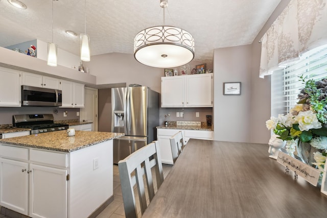 5718 Brook Hollow Dr, Hilliard, OH 43026 - kitchen with stainless steel appliances, a textured ceiling, white cabinetry, light stone countertops, and hanging light fixtures