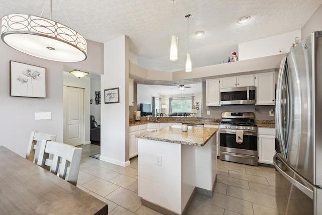 5718 Brook Hollow Dr, Hilliard, OH 43026 - kitchen with appliances with stainless steel finishes, a textured ceiling, light tile patterned flooring, a kitchen island, and white cabinets