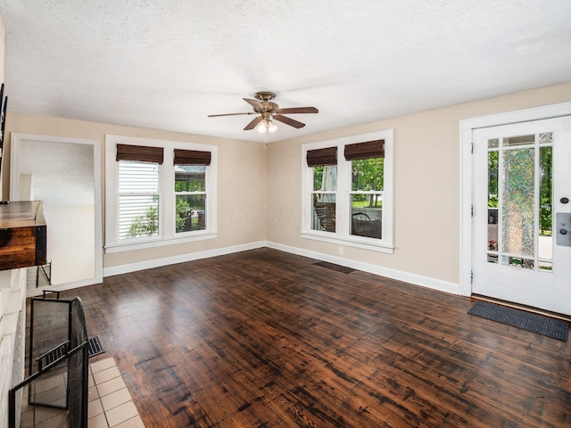 34 Columbus Ave, Delaware, OH 43015 - unfurnished living room featuring ceiling fan, plenty of natural light, baseboards, dark wood-type flooring, and a textured ceiling