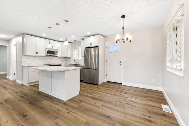 3998 Scioto Darby Creek Rd, Hilliard, OH 43026 - kitchen with stainless steel appliances, a chandelier, backsplash, white cabinets, and a kitchen island