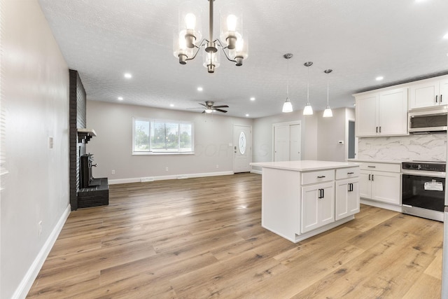 3998 Scioto Darby Creek Rd, Hilliard, OH 43026 - kitchen with stainless steel appliances, a fireplace, tasteful backsplash, light countertops, and white cabinetry