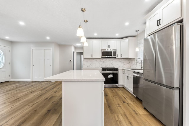 3998 Scioto Darby Creek Rd, Hilliard, OH 43026 - kitchen with stainless steel appliances, a sink, a center island, backsplash, and light wood-style flooring