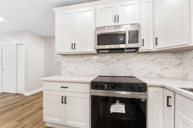 3998 Scioto Darby Creek Rd, Hilliard, OH 43026 - kitchen featuring stainless steel microwave, range with electric cooktop, light wood-type flooring, decorative backsplash, and baseboards