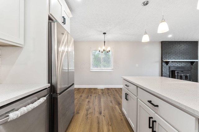 3998 Scioto Darby Creek Rd, Hilliard, OH 43026 - kitchen with stainless steel appliances, baseboards, wood finished floors, white cabinetry, and a brick fireplace