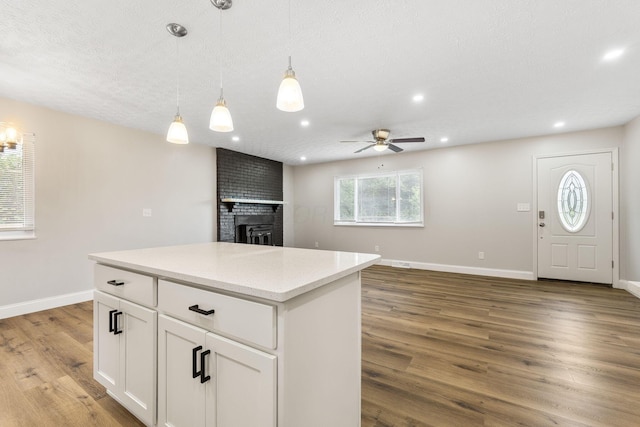 3998 Scioto Darby Creek Rd, Hilliard, OH 43026 - kitchen with ceiling fan, wood finished floors, baseboards, white cabinetry, and a brick fireplace
