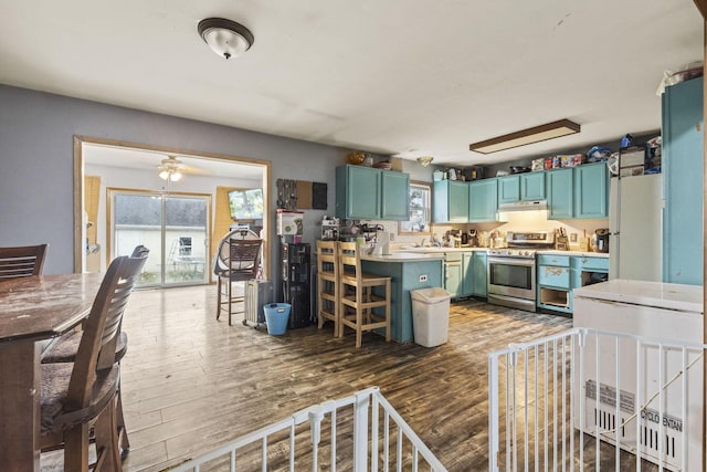 217 N Yencer St, Baltimore, OH 43105 - kitchen with stainless steel range oven, wood finished floors, under cabinet range hood, a peninsula, and a kitchen breakfast bar