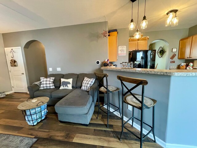6231 Red Glare Dr Unit 287, Galloway, OH 43119 - kitchen with black fridge with ice dispenser, arched walkways, dark wood-style floors, a breakfast bar area, and light brown cabinets