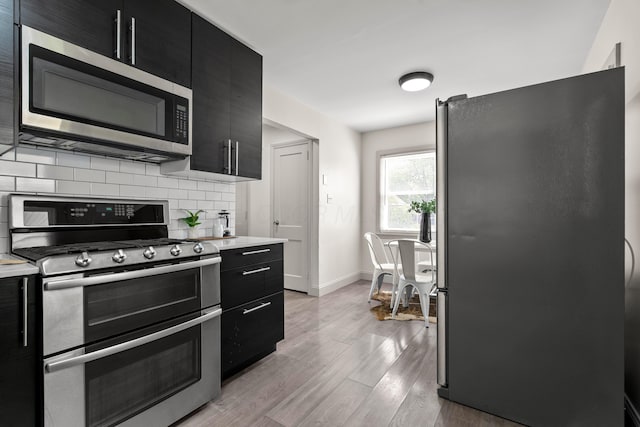 3091 Azelda St, Columbus, OH 43224 - kitchen featuring appliances with stainless steel finishes, dark cabinets, tasteful backsplash, and light countertops