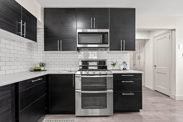 3091 Azelda St, Columbus, OH 43224 - kitchen with dark cabinetry, stainless steel appliances, light countertops, and decorative backsplash