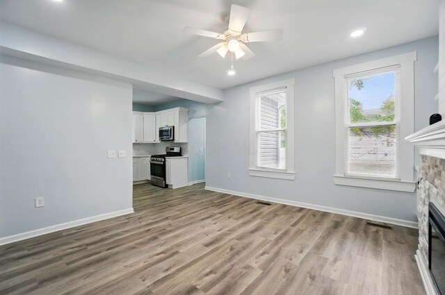 517 S Champion Ave, Columbus, OH 43205 - unfurnished living room with a stone fireplace, wood finished floors, ceiling fan, baseboards, and recessed lighting