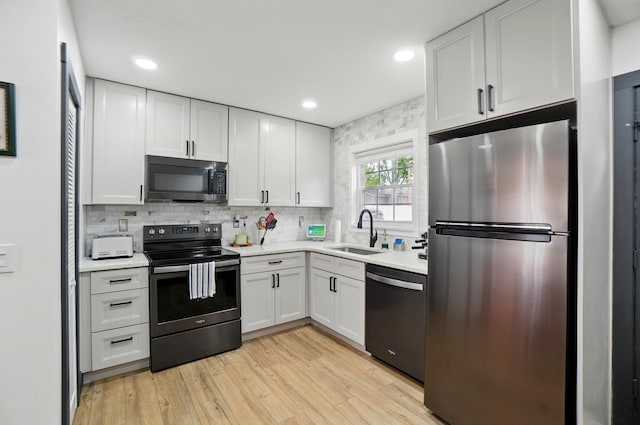 538 S Otterbein Ave Unit 2E, Westerville, OH 43081 - kitchen featuring black appliances, a sink, white cabinets, light wood finished floors, and backsplash