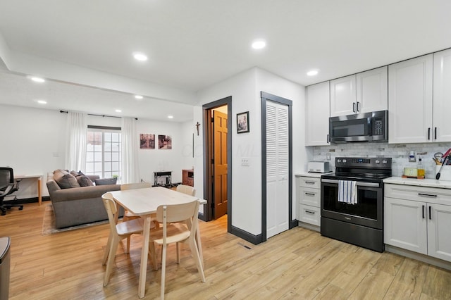 538 S Otterbein Ave Unit 2E, Westerville, OH 43081 - kitchen with stainless steel microwave, black electric range oven, light wood-type flooring, backsplash, and recessed lighting