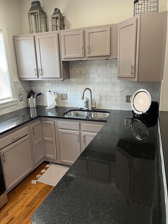 323 E Kossuth St, Columbus, OH 43206 - kitchen featuring a sink, light wood finished floors, backsplash, dark stone countertops, and gray cabinets