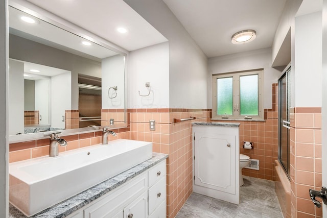 2105 Chardon Rd, Columbus, OH 43220 - bathroom featuring tile walls, toilet, vanity, shower / bath combination with glass door, and a wainscoted wall