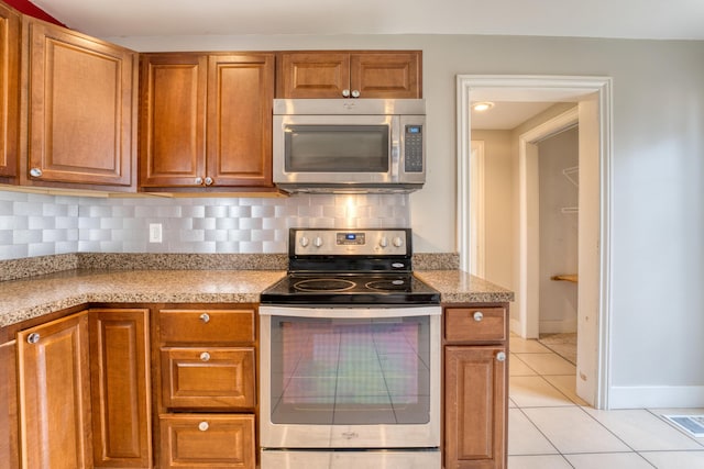 216 N St, Utica, OH 43080 - kitchen with stainless steel appliances, light tile patterned flooring, backsplash, and brown cabinets