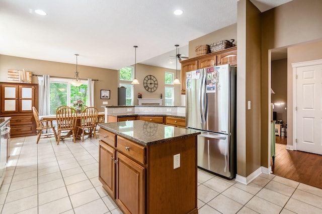 5673 Sugarwood Dr, New Albany, OH 43054 - kitchen with freestanding refrigerator, light tile patterned flooring, a peninsula, brown cabinetry, and a ceiling fan