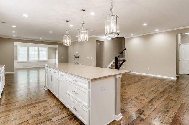 7839 Eastcross Dr, New Albany, OH 43054 - kitchen featuring ornamental molding, open floor plan, wood finished floors, a kitchen island, and white cabinetry