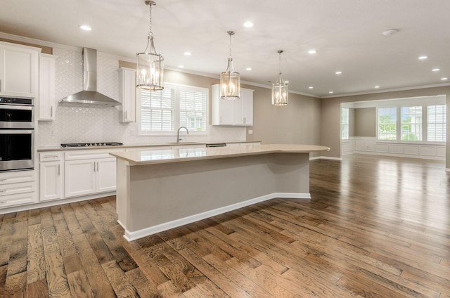 7839 Eastcross Dr, New Albany, OH 43054 - kitchen featuring wall chimney range hood, ornamental molding, a sink, double oven, and a center island