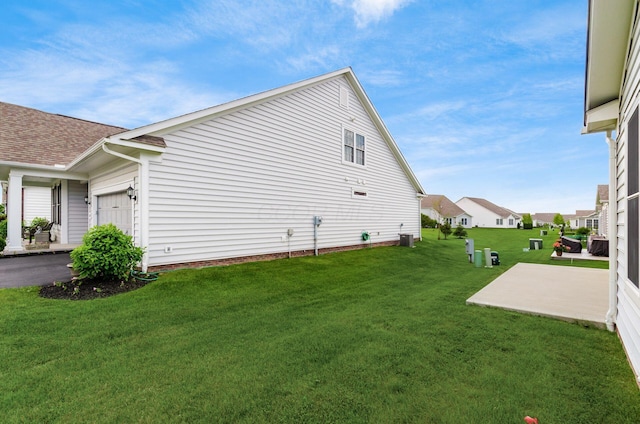 7839 Eastcross Dr, New Albany, OH 43054 - view of side of home featuring a lawn, an attached garage, a shingled roof, central AC, and a patio