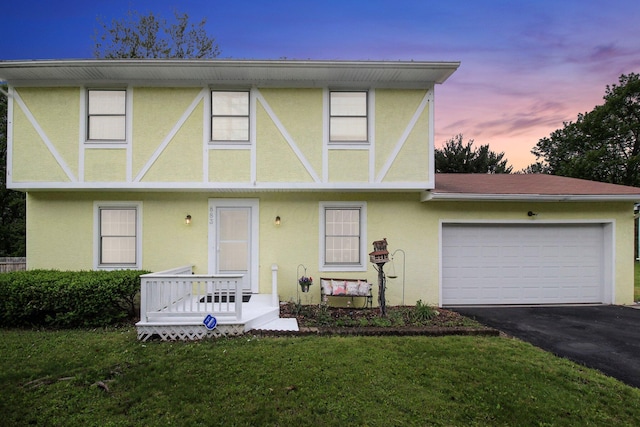 883 Mcnaughten Rd, Columbus, OH 43213 - tudor house with stucco siding, asphalt driveway, an attached garage, and a yard