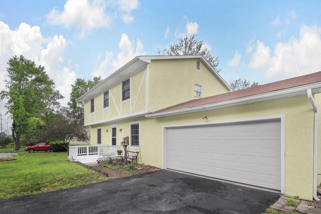 883 Mcnaughten Rd, Columbus, OH 43213 - view of front of house with stucco siding, asphalt driveway, a front lawn, and a garage