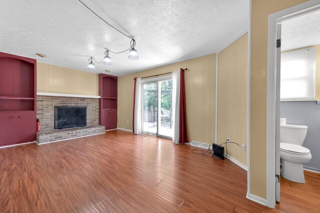 883 Mcnaughten Rd, Columbus, OH 43213 - unfurnished living room featuring a textured ceiling, wood finished floors, and a brick fireplace