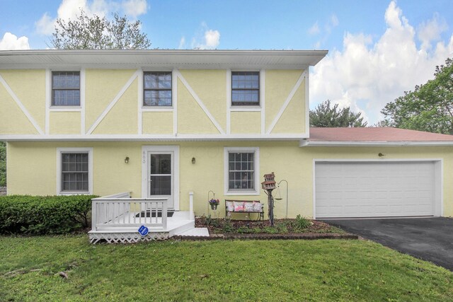 883 Mcnaughten Rd, Columbus, OH 43213 - tudor house with stucco siding, asphalt driveway, a garage, and a front yard