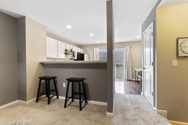 5290 Berthold Pass Dr, Dublin, OH 43016 - kitchen with stainless steel microwave, light carpet, a kitchen breakfast bar, white cabinets, and fridge
