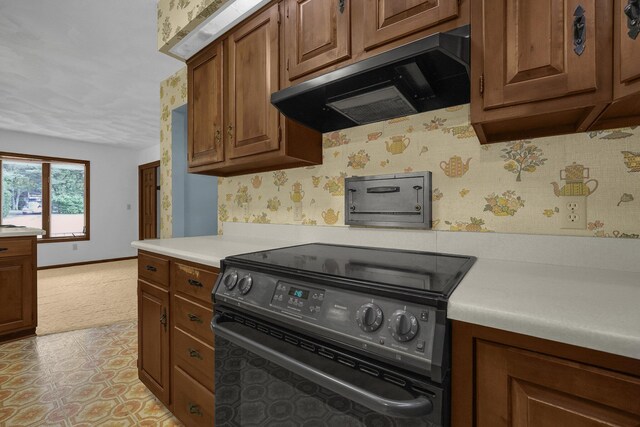 363 Carroll Eastern Rd NW, Baltimore, OH 43105 - kitchen with black electric range oven, extractor fan, light countertops, brown cabinetry, and wallpapered walls