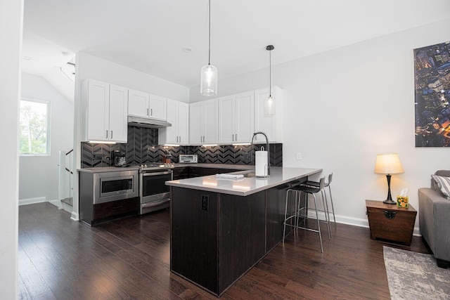 199 E 5th Ave, Columbus, OH 43201 - kitchen featuring appliances with stainless steel finishes, under cabinet range hood, a peninsula, backsplash, and white cabinets