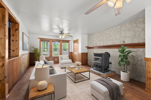 11007 Hebron Rd, Buckeye Lake, OH 43008 - living room with a ceiling fan, a wood stove, a wainscoted wall, wood finished floors, and wooden walls