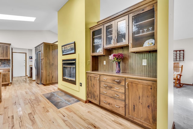 3753 Homer Rd NW, Utica, OH 43080 - kitchen with freestanding refrigerator, vaulted ceiling, a skylight, glass insert cabinets, and light wood-style flooring