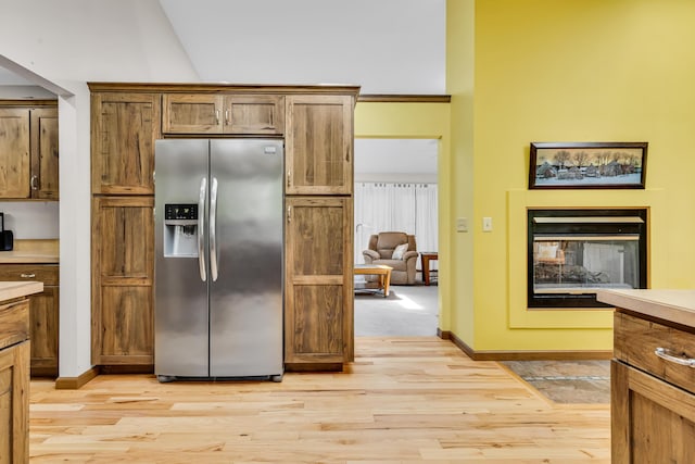 3753 Homer Rd NW, Utica, OH 43080 - kitchen with stainless steel refrigerator with ice dispenser, light wood finished floors, a multi sided fireplace, baseboards, and light countertops