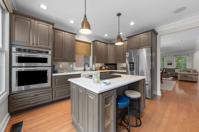 1054 Perry St, Columbus, OH 43201 - kitchen with stainless steel appliances, light countertops, a sink, tasteful backsplash, and crown molding