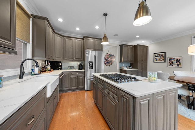 1054 Perry St, Columbus, OH 43201 - kitchen with appliances with stainless steel finishes, a sink, ornamental molding, light wood finished floors, and decorative backsplash
