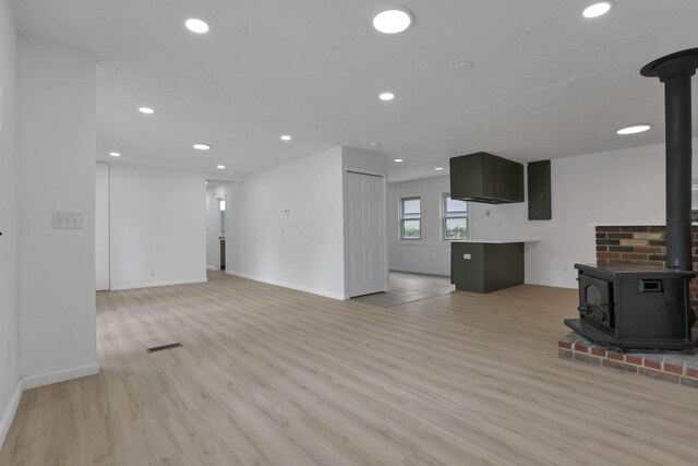 366 Orchard Ln, Sunbury, OH 43074 - unfurnished living room featuring a wood stove, light wood-style floors, recessed lighting, and baseboards