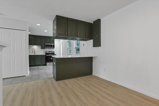 366 Orchard Ln, Sunbury, OH 43074 - kitchen with stainless steel appliances, baseboards, light wood finished floors, a peninsula, and a sink