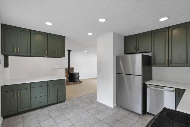 366 Orchard Ln, Sunbury, OH 43074 - kitchen with green cabinetry, stainless steel appliances, a wood stove, light countertops, and recessed lighting