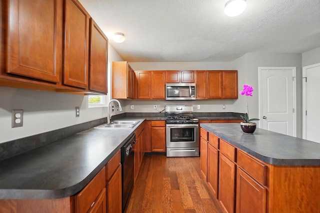 218 Christian St, Delaware, OH 43015 - kitchen with stainless steel appliances, dark countertops, a sink, dark wood finished floors, and brown cabinetry