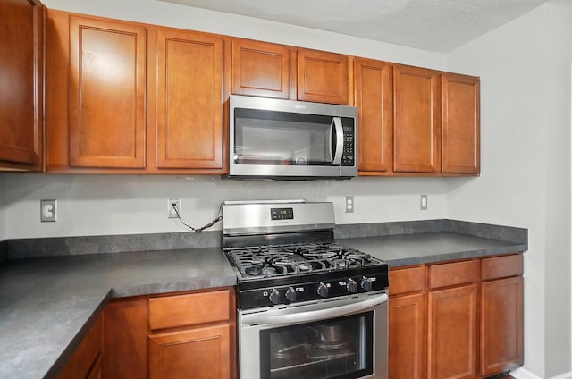 218 Christian St, Delaware, OH 43015 - kitchen featuring stainless steel appliances, dark countertops, and brown cabinetry