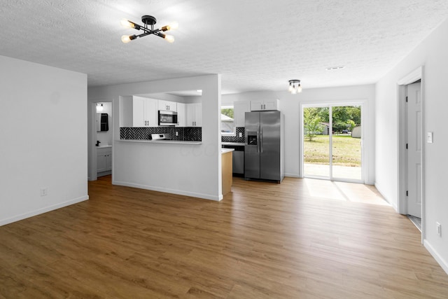 70 5th Ave SW, Etna, OH 43062 - kitchen featuring appliances with stainless steel finishes, a chandelier, light wood finished floors, white cabinetry, and a textured ceiling