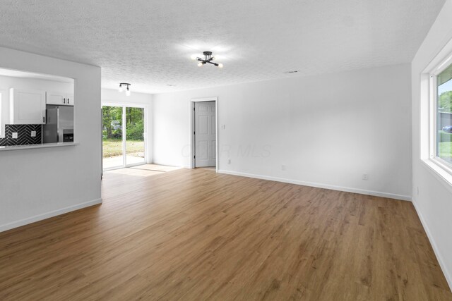 70 5th Ave SW, Etna, OH 43062 - unfurnished living room featuring light wood-style floors, a textured ceiling, and baseboards